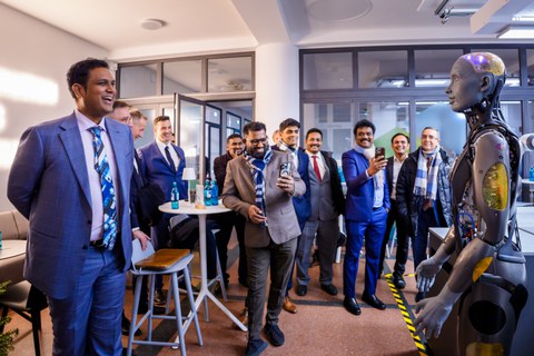 Fotoaufnahmen von mehreren Menschen, darunter der indische Botschafter in Deutschland, Ajit Gupte, bei einer Präsentation eines Roboters.