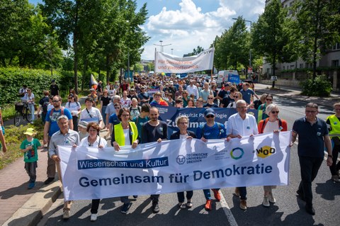 Fotoaufnahme eines Demonstrationszuges. In der ersten Reihe tragen Menschen ein Banner dem "Gemeinsam für Demokratie" steht.