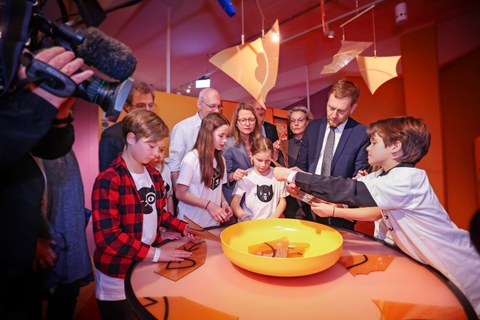 Eine Gruppe von Kindern und Erwachsenen steht um einen Tisch, auf dem eine Schüssel mit Chips steht.