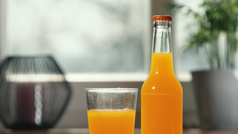 Foto einer Flasche und eines Glases mit Orangenlimonade.