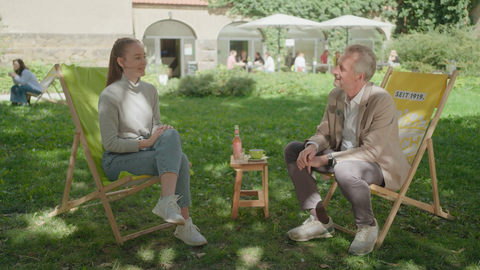 Fotoaufnahme von Wirtschaftswissenschaftler Alexander Kemnitz, der im Freien auf einem Liegestuhl sitzt und mit einer Frau spricht.