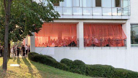 Fotoaufnahme von zahlreichen Menschen, die sich im Eingangsbereich eines Bürogebäudes aufhalten.