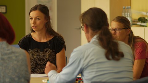 3 junge Frauen sitzen gemeinsam an einem Tisch.