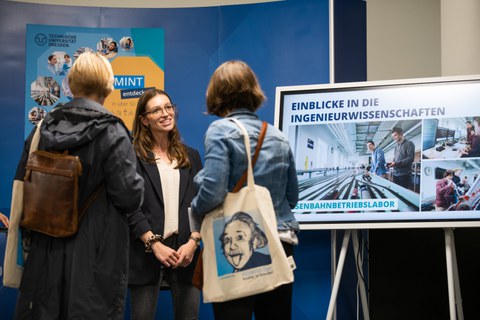 Fotoaufnahme von drei Menschen, die an einem Stand der Ingenieurwissenschaften der TU Dresden miteinander im Gespräch sind.