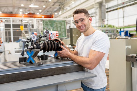 Fotoaufnahme eines jungen Mannes, der in einem Labor an einer Maschine steht.