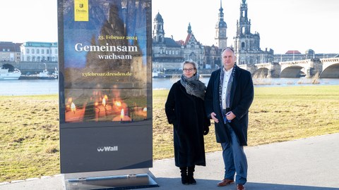 Prof. Ursula Staudinger, Rektorin der TU Dresden, und Dirk Hilbert, Oberbürgermeister der Stadt Dresden, stehen im Freien vor der Kulisse der Dresdner Altstadt. Neben ihnen ist ein Plakat ausgestellt, das auf die Veranstaltung am 13. Februar verweist.