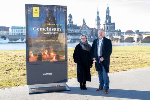 Prof. Ursula Staudinger, Rektorin der TU Dresden, und Dirk Hilbert, Oberbürgermeister der Stadt Dresden, stehen im Freien vor der Kulisse der Dresdner Altstadt. Neben ihnen ist ein Plakat ausgestellt, das auf die Veranstaltung am 13. Februar verweist.