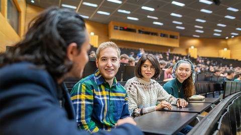 Junge Studierende in einer Sitzreihe des Hörsaals Audimax.