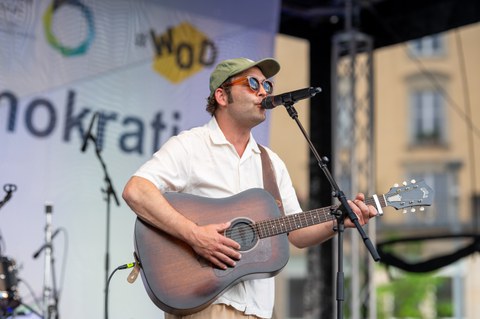 Nahaufnahme des Musikers Bosse auf einer Bühne am Mikrofon mit Gitarre.