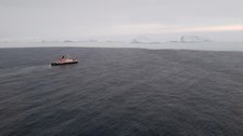 im Vordergrund ein Schiff, im Hintergrund erhebt sich die Eiskante,