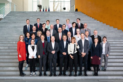 Gruppenbild auf einer Treppe. In der ersten Reihe Bundeskanzler Scholz.