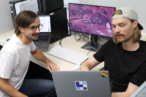 Foto von Marco Gustav, Erstautor der Veröffentlichung und Wissenschaftlicher Mitarbeiter am EKFZ für Digitale Gesundheit, und Dr. Nic G. Reitsam, Co-Autor und Pathologe an der Medizinischen Fakultät der Universität Augsburg. Beide besprechen die Daten der Studie.