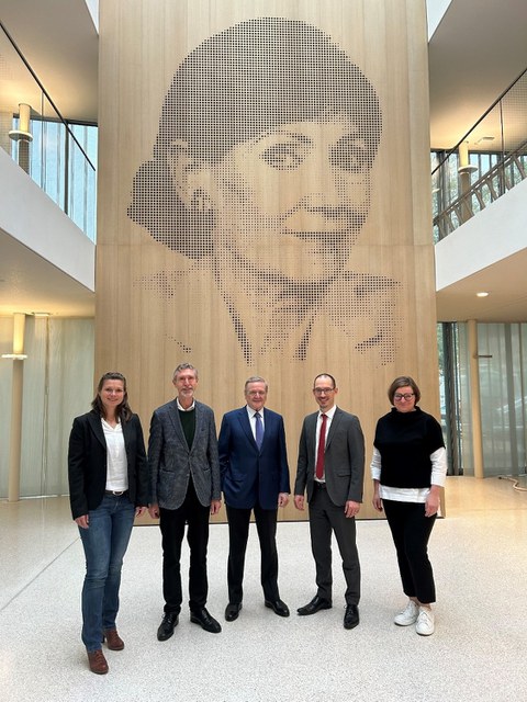 Gruppenfoto zum Präsentationstermin des Vorhabens „Nachwuchsgruppe waldbezogene Umweltkommunikation“ bei der Eva Mayr-Stihl Stiftung vor dem Portrait der Stifterin Eva Mayr-Stihl.