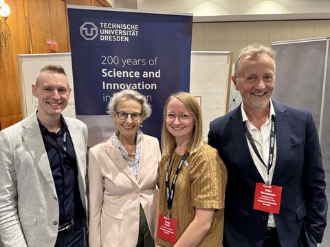 Jeremiah Peterson vom Alumni-Büro der TUD, Rektorin Prof. Ursula Staudinger, Alumni-Botschafterin Romy Frank und Peter Rosenbaum vom International Office stehen vor einem Banner der TU Dresden.