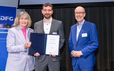 Foto des TUD-Wissenschaftlers Marco Salvalagio bei der Preisverleihung mit der DFG-Generalsekretärin Heide Ahrens (l.) und dem Laudator Kai Sundmacher (r.).