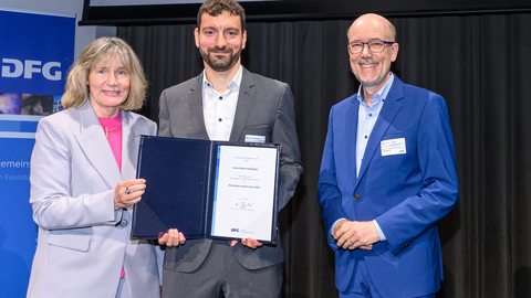 Foto des TUD-Wissenschaftlers Marco Salvalagio bei der Preisverleihung mit der DFG-Generalsekretärin Heide Ahrens (l.) und dem Laudator Kai Sundmacher (r.).