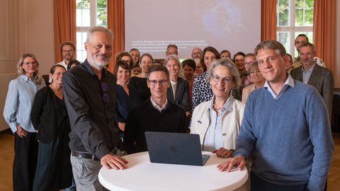 Fotoaufnahme von Christoph Schletterer (Sachgebiet 7.1 Corporate Design), Jan Röder (Leiter Sachgebiet Strategie), Prof.in Ursula Staudinger (Rektorin) und Dr. Volker Balli (Geschäftsführer Geschäftsbereich Universitätsentwicklung) und weitere Beteiligte beim Get-together zur Einreichung des Selbstberichts.