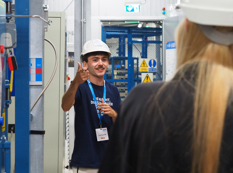 Foto eines Mannes, der am Teilchenbeschleuniger im Felsenkeller zu einer kleinen Menschengruppe spricht.