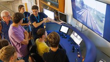 Foto vom Eisenbahnsimulator der TU Dresden, an dem sich eine kleine Menschengruppe befindet.