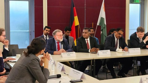 Foto von Prof. Wolfgang Nagel in einer Gesprächssituation mit mehreren Personen, die an Tischen sitzen.