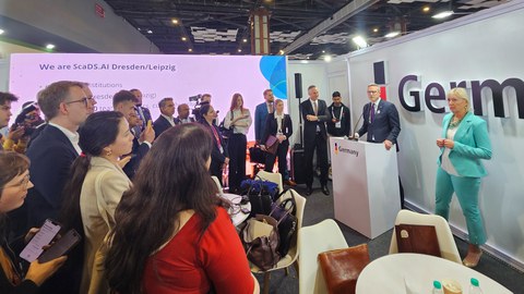 Fotoaufnahme von Bundesminister Karsten Wildberger, der im deutschen Pavillon an einem Pult stehend zu einer Gruppe von Menschen spricht.