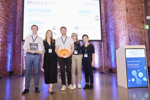 The photo shows the five-strong MaculaPatch team with their award and an eye model in front of the GeneNovate® stage at the Allerheiligen Hofkirche in Munich