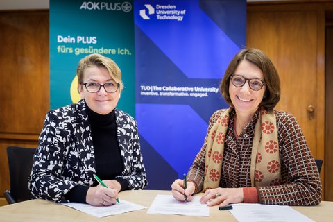 Jana Maywald (l.), Leiterin des Regionalcenters Dresden der AOK PLUS, und Prof.in Roswitha Böhm, Prorektorin Universitätskultur und Internationalisierung der TUD, beim Unterzeichnen der Vereinbarung. 