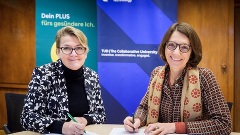 Jana Maywald (l.), Leiterin des Regionalcenters Dresden der AOK PLUS, und Prof.in Roswitha Böhm, Prorektorin Universitätskultur und Internationalisierung der TUD, beim Unterzeichnen der Vereinbarung. 