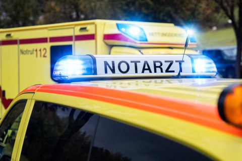 Foto von einem Notarzt und einem Rettungswagen. Bei beiden Fahrzeugen ist das Blaulicht angeschaltet.