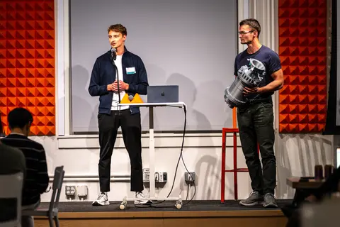 Zwei Personen bei einer Präsentation auf einer Bühne.
