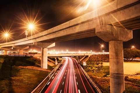 Das Foto zeigt unscharf die Lichter und den schnellen Verkehr auf einer Autobahn in der Nacht.