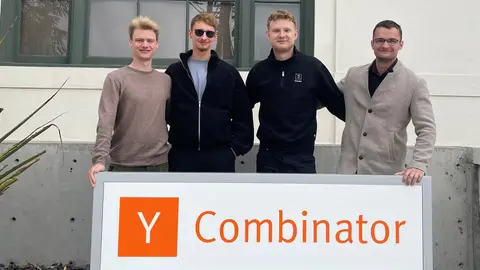 Felix Kelm, Charlie Weise, Matty Driesnack und Paul Kunhart stehen hinter einem Schild, auf dem "Y Combinator" steht.