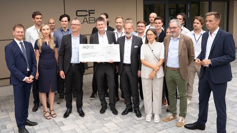 Mehrere Personen stehen vor dem neuen CFLab bei der symbolischen Schlüsselübergabe für das Gebäude darunter Sachsens Ministerpräsident Michael Kretschmer und TUD-Kanzler Jan Gerken.