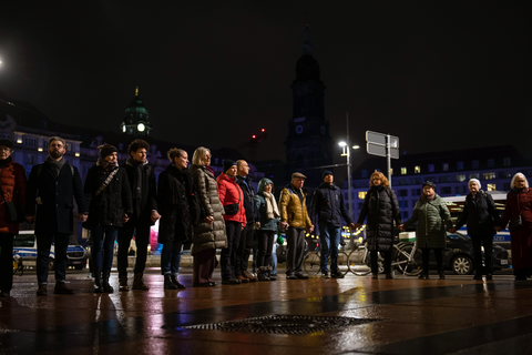 Fotoaufnahme von mehreren Personen, die sich vor dem Dresdner Altmarkt die Hände reichen und eine Menschenkette bilden.