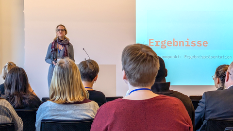 Foto von Prof.in Marianne Kneuer, die auf einer Bühne steht und zu Publikum spricht.