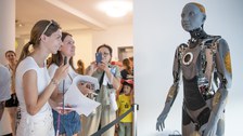 Mehrere Menschen stehen vor einem lebensgroßen humanoiden Roboter in einem Ausstellungsraum. Zwei Personen sprechen gerade in ein Mikrofon, andere fotografieren oder beobachten den Roboter aufmerksam.