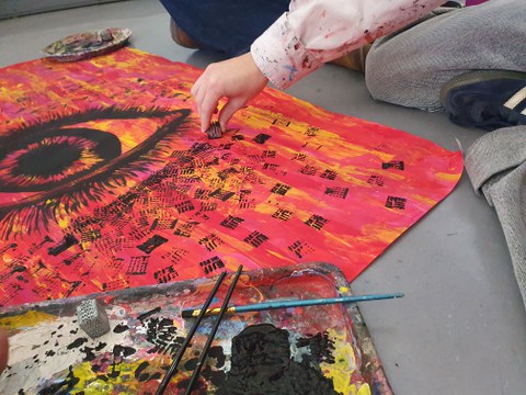 Ein schwarzes Auge auf rotem Hintergrund wird gemalt.