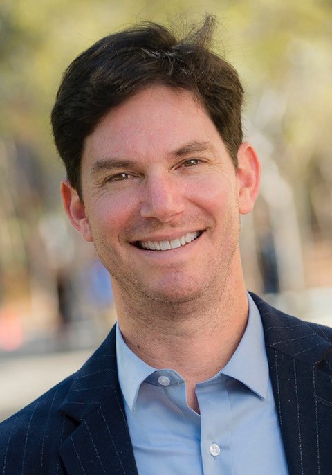 The image is a portrait of Prof. Seth Cohen, with a blurred background.