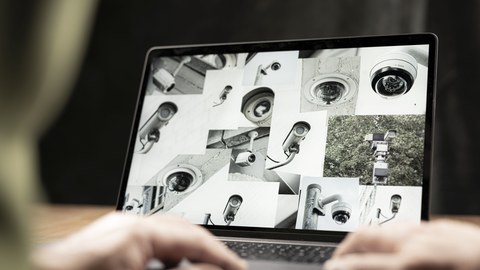 Aufgeklappter Laptop mit einer Collage aus Bildern von Überwachungskameras