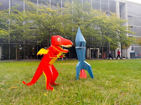 A cardboard dragon and rocket stand before the Auditorium Center.