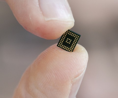 Großaufnahme eines elektronischen Chips, gehalten zwischen Daumen und Zeigefinger