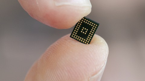 Großaufnahme eines elektronischen Chips, gehalten zwischen Daumen und Zeigefinger