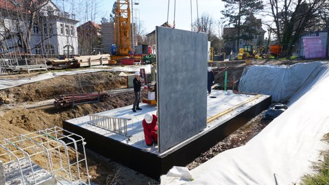 Baustelle, auf eine Bodenplatte wird eine senkrechte Betonscheibe aufgebracht.