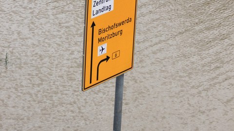 Ein Straßenschild/Wegweiser steht in einer Wassermasse.