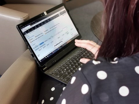 Eine Frau in einer gepunkteten Bluse sitzt vor einem Laptop
