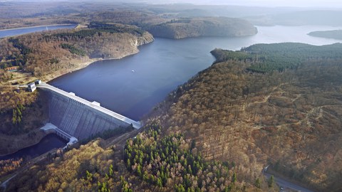 Foto einer Talsperre mit bewaldeten Ufern.