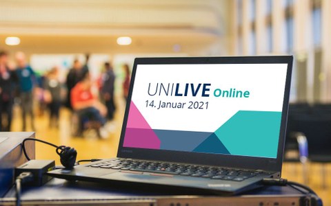 Ein aufgeklappter Laptop, auf dem Display ist das Logo von UNI Live zu sehen.