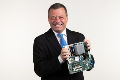 Porträtfoto Professor Lehner, er hält ein elektronisches Bauteil in der Hand.
