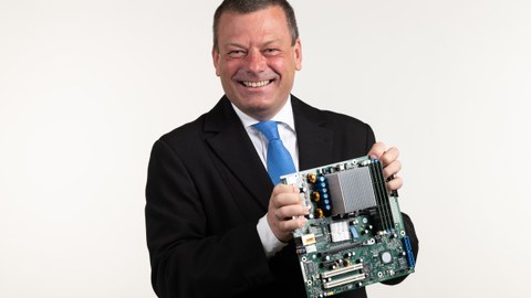 Porträtfoto Professor Lehner, er hält ein elektronisches Bauteil in der Hand.