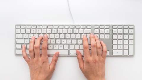 Eine rechte und eine linke Hand auf einer weißen Tastatur.